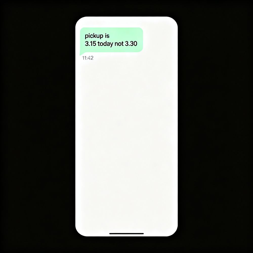 A phone on a desk showing a message: pickup is 3.15 today not 3.30